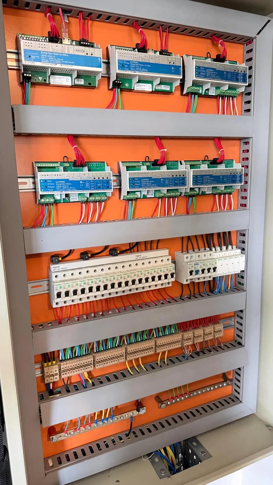 Quadro elétrico de automação de iluminação com módulos Lutron em trilho e fiação identificada.