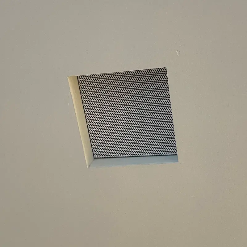 Caixa acústica quadrada de embutir no forro, com grade discreta, na Mostra Magna Audio.