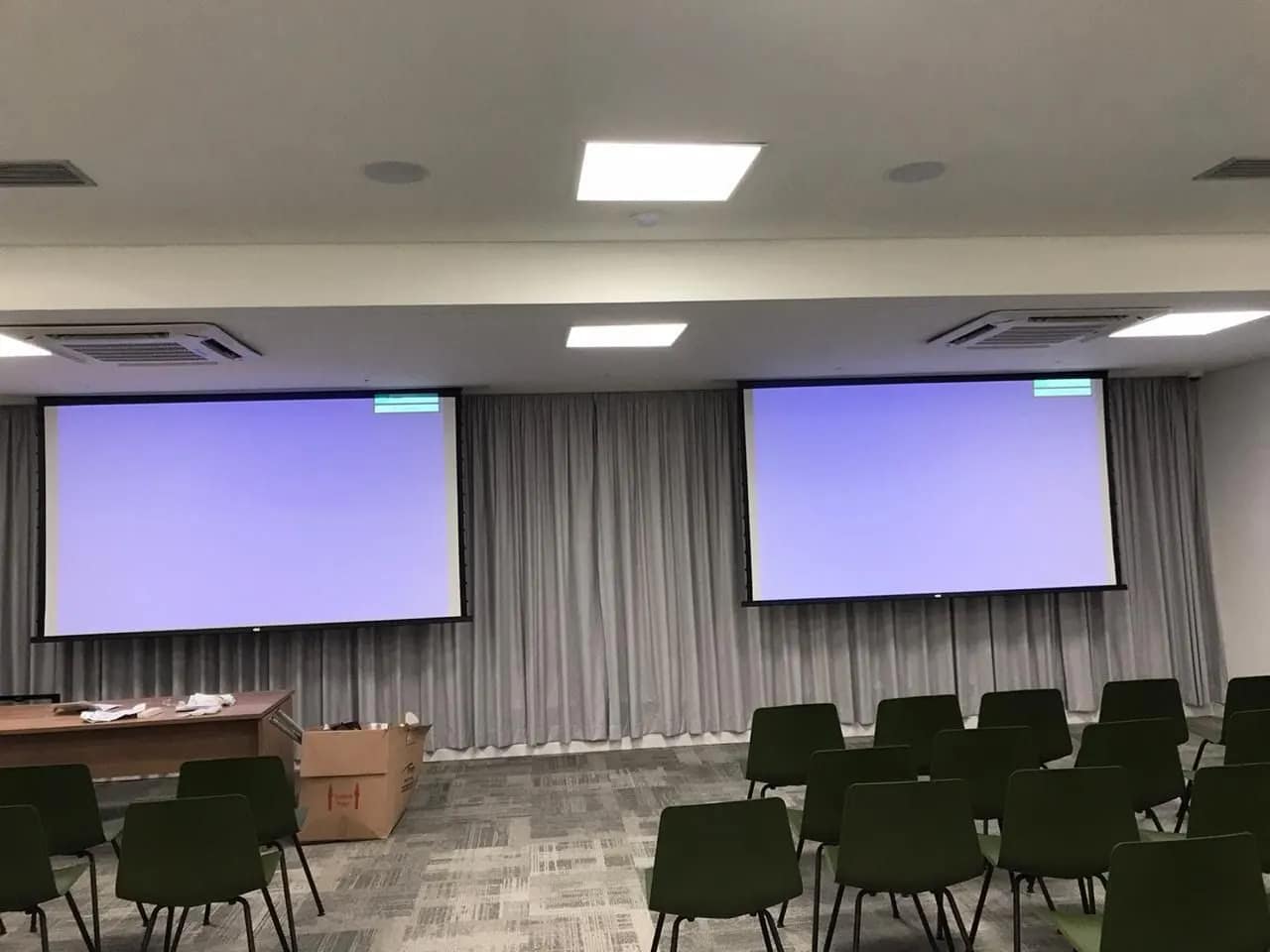 Sala de treinamento com duas telas de projeção lado a lado.