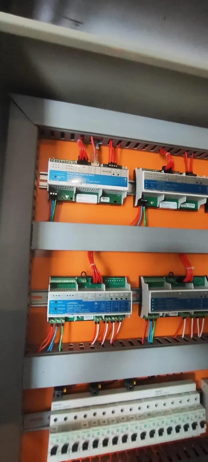Quadro de automação aberto, com módulos de iluminação em trilho e cabeamento identificado.