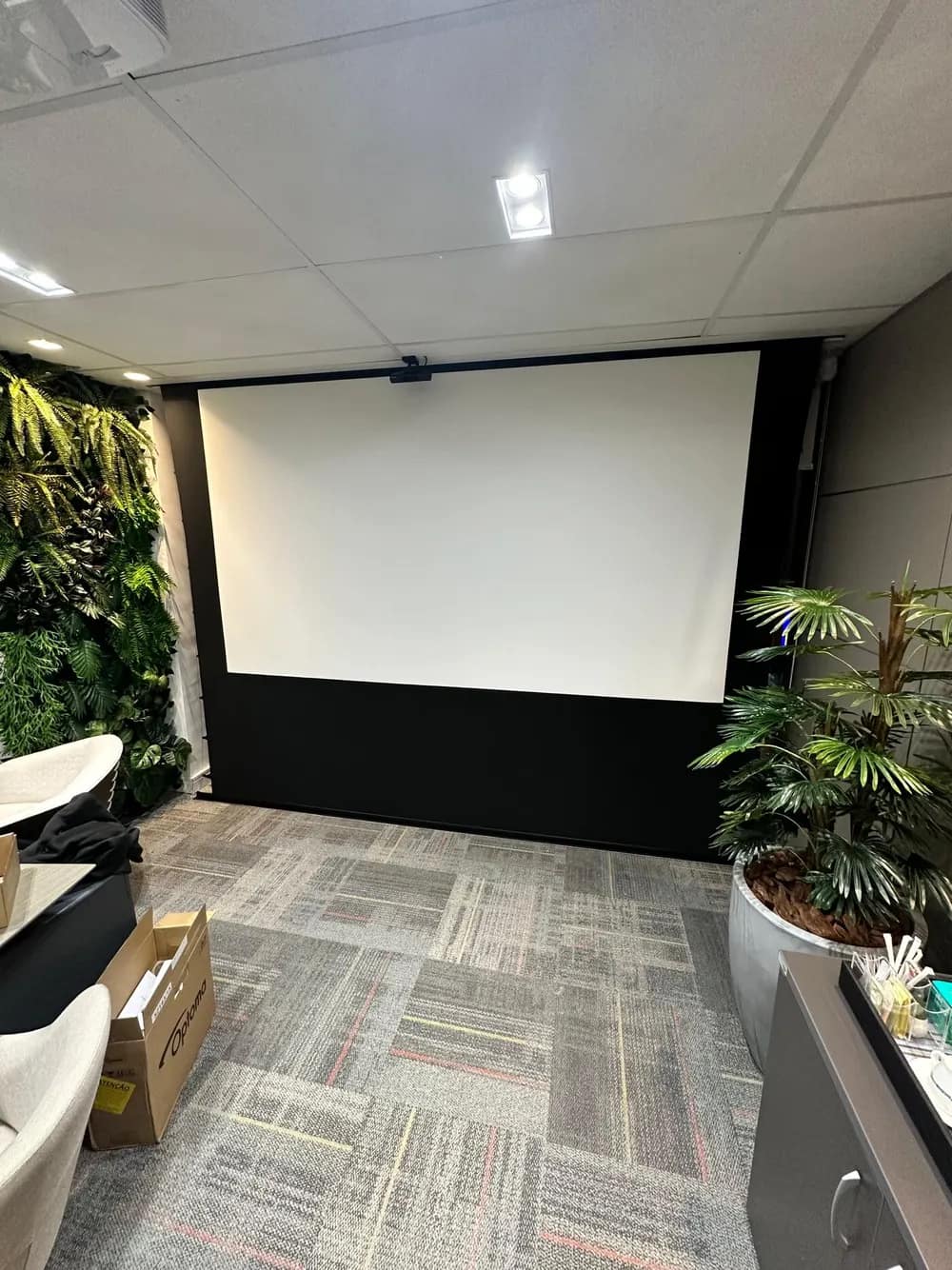 Sala com tela de projeção descida para apresentação.
