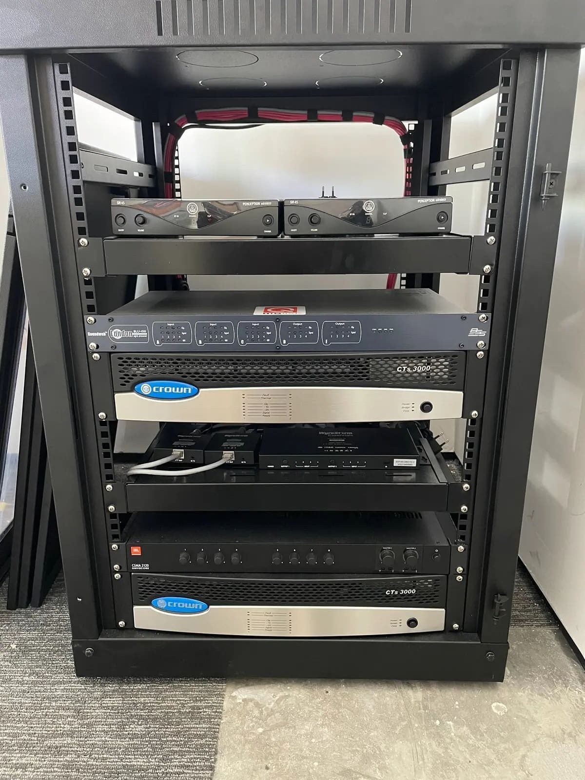 Rack de áudio e vídeo organizado, com os equipamentos acessíveis pela frente.