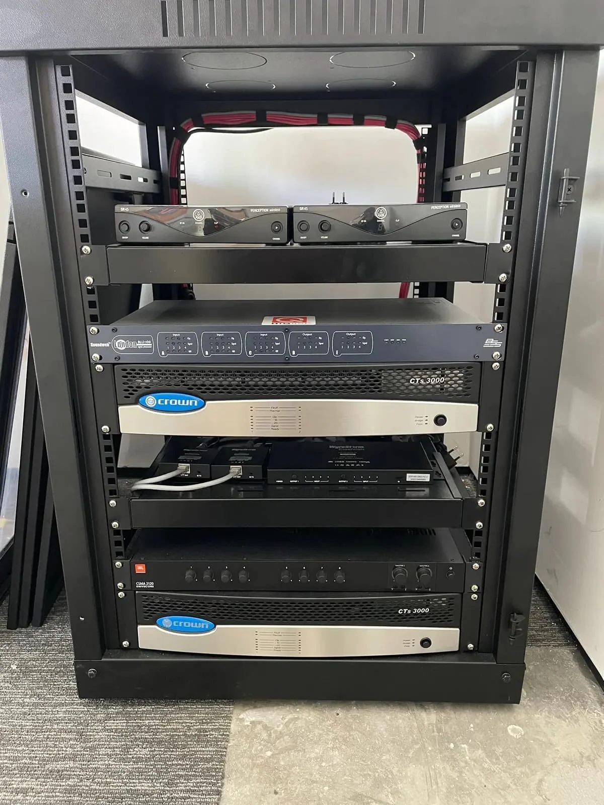Rack de áudio e vídeo organizado, com os equipamentos acessíveis pela frente.