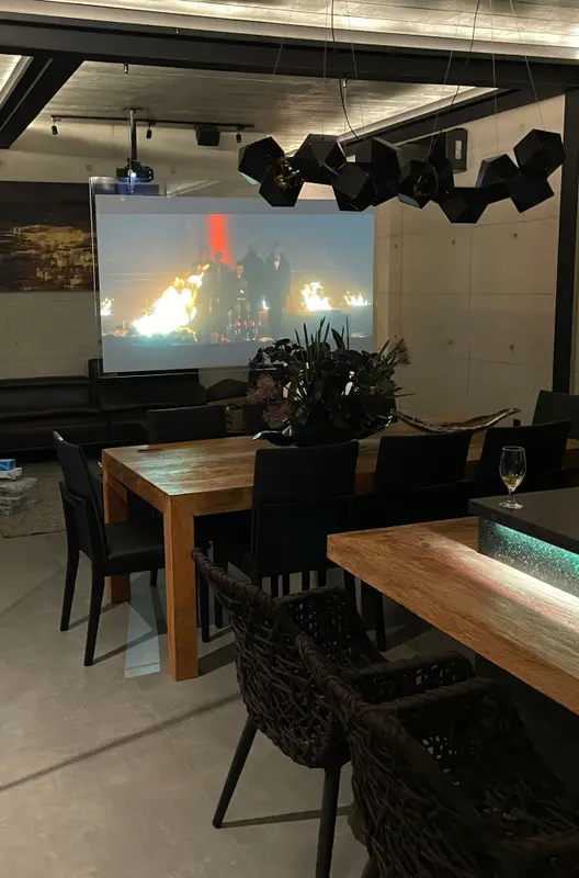 Projeção em tela suspensa no espaço gourmet, sobre a mesa de jantar, com projetor no teto.