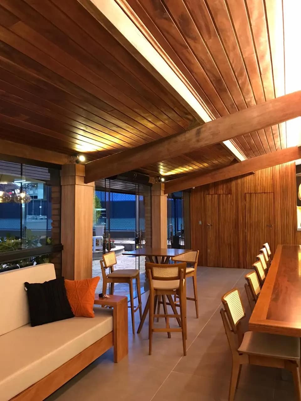 Varanda com forro de madeira e iluminação indireta.