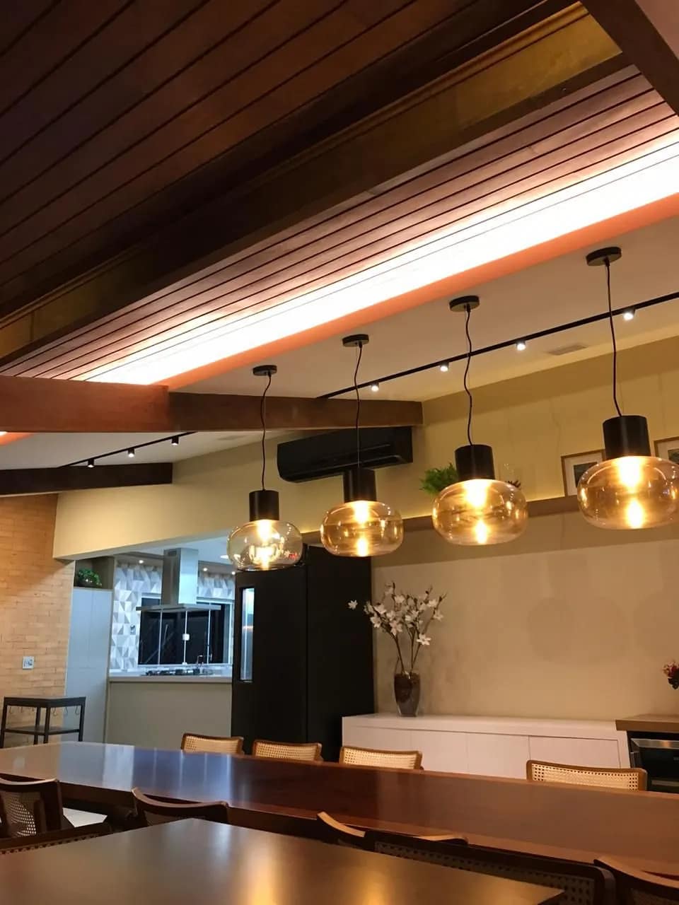 Área gourmet com pendentes acesos e iluminação embutida no forro.