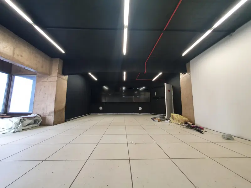 Sala de crise vazia em obra, com piso elevado, forro escuro e paredes ainda sem o video wall.