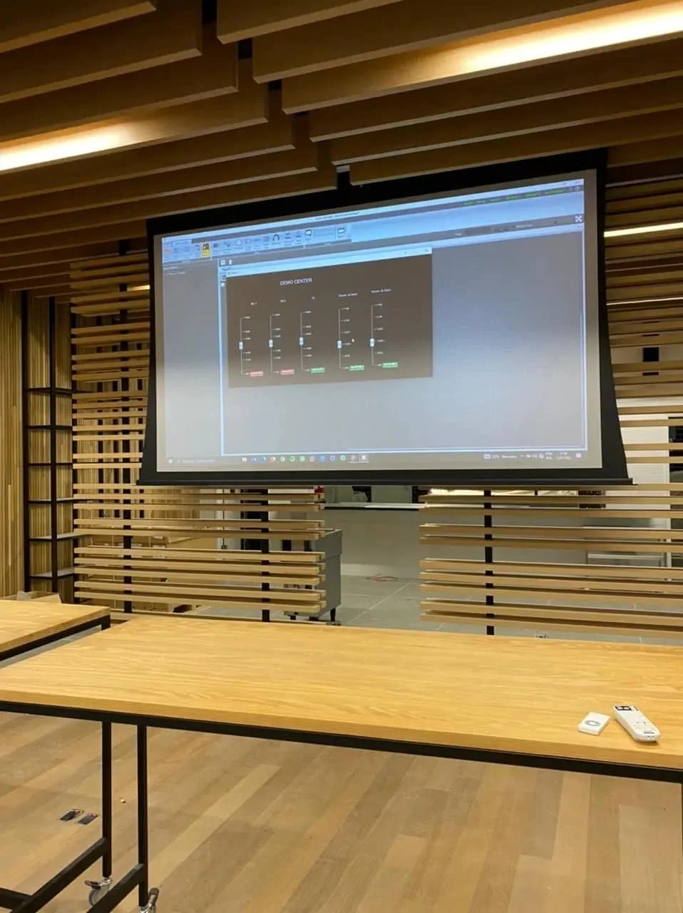 Sala de treinamento com tela de projeção e bancada de madeira.